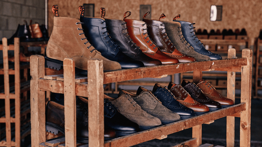 A mixture of LANX, goodyear welted, grey, brown and tan, derby boots and shoes on a wooden shoe rack.