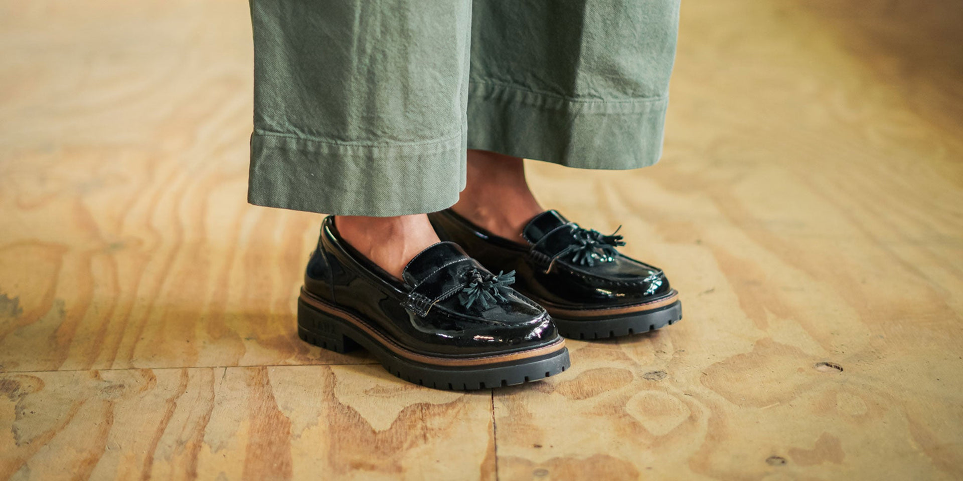 A woman sat on a rug wearing the Calder Anthracite, gum soled, derby shoes.