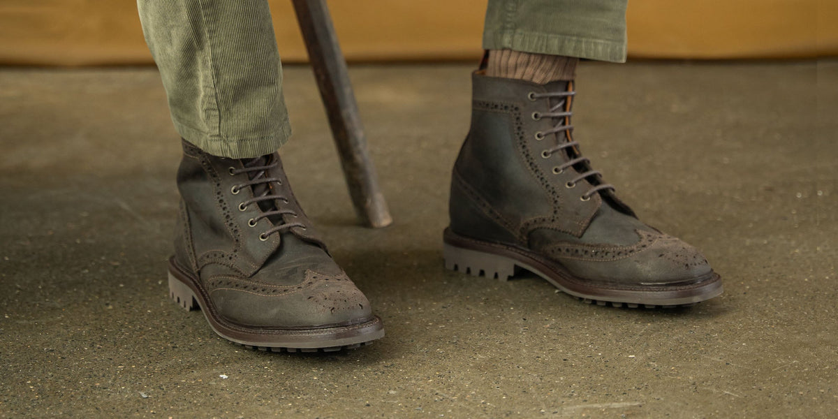 A mixture of LANX, goodyear welted, grey, brown and tan, derby boots and shoes on a wooden shoe rack.