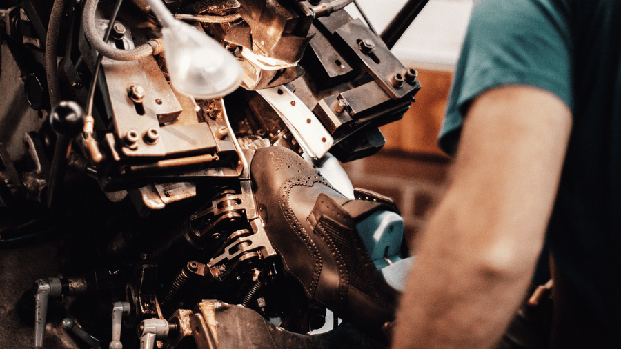 A british cobler using a toe lasting machine, to create LANX brogues.