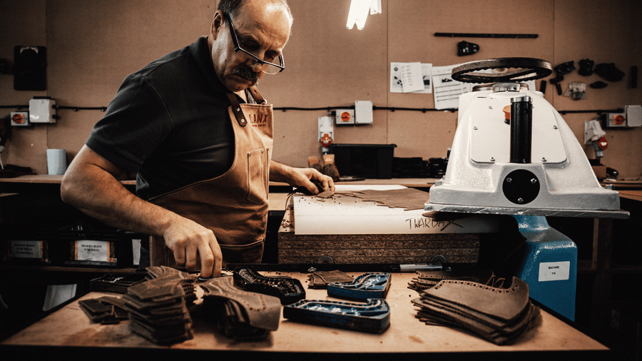 An english colber stitching brogueing on to LANX shoes, with stacks of brogueing to his side.