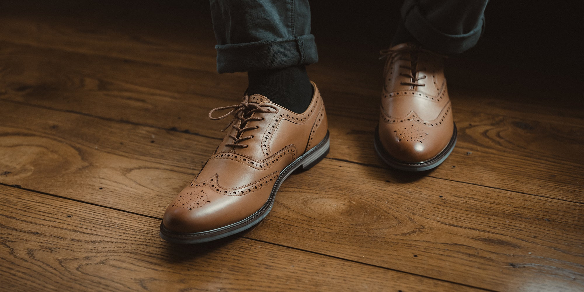 A man wearing the LANX Shireburn Khaki & Brown, oxford brogue shoes. Stood on a concrete floor with a rug.