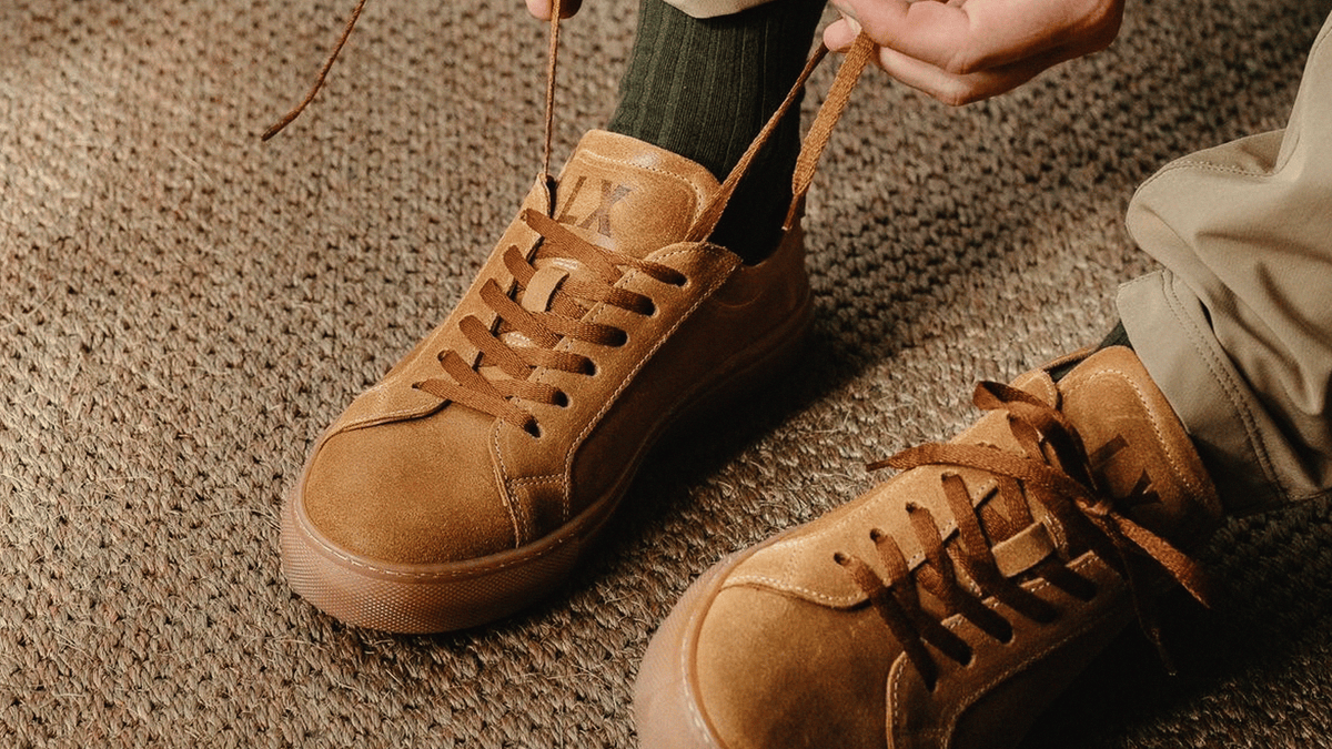 A close up shot of a man's feet, wearing the LANX, Ancoats // Date & Gum, suede sneakers.