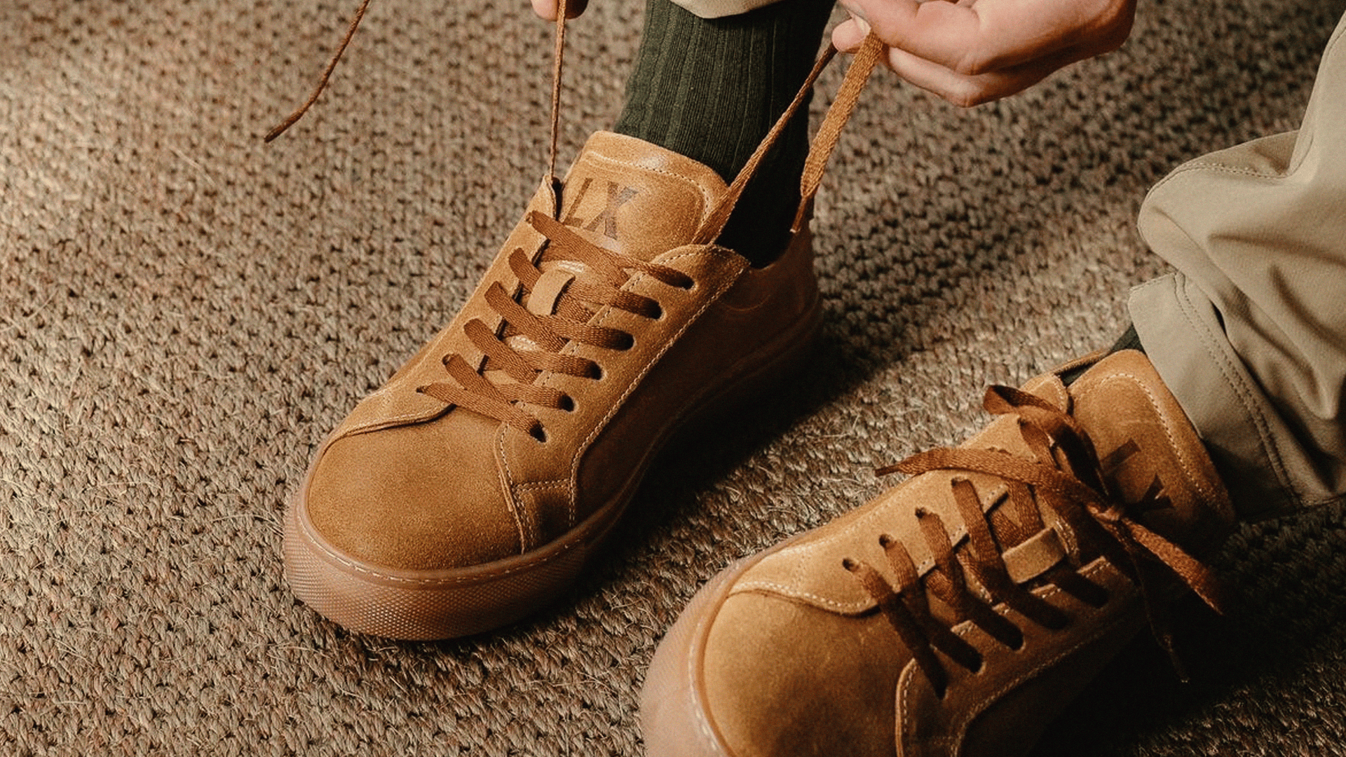 A close up shot of a man's feet, wearing the LANX, Ancoats // Date & Gum, suede sneakers.
