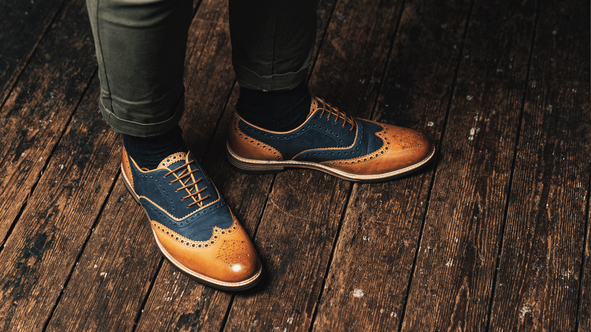 An above view of a man's feet, wearing the LANX, Shireburn // Navy & Tan, oxford brogues.