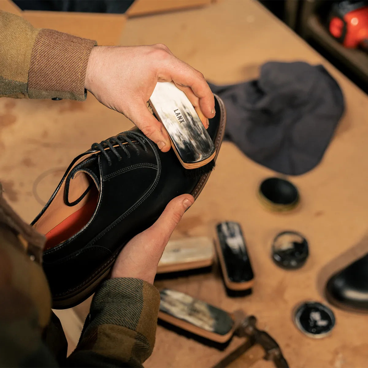 Image of a black shoe being polished with a LANX Cleasby shoe brush