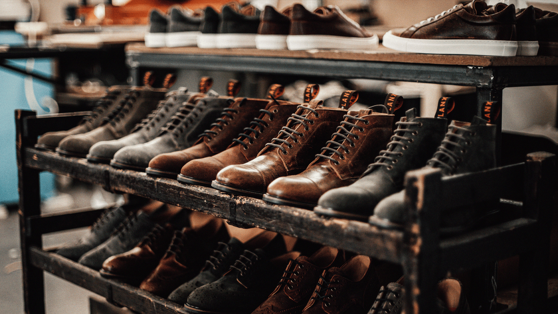 Various brown, grey and burgundy, derby boots and shoes on a wooden shoe rack. All part of the LANX Charle's F. Stead collection.