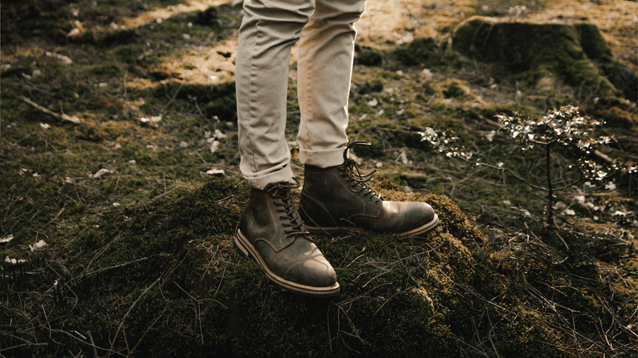 A man stood on a mossy tree stump wearing the LANX, Bamber // Brown Distressed, goodyear welted, toe cap, derby boots.
